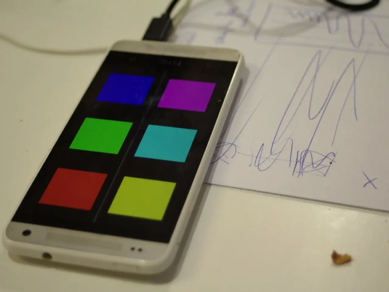 In this image, we can see a white color table, on that table there is a mobile phone which is...