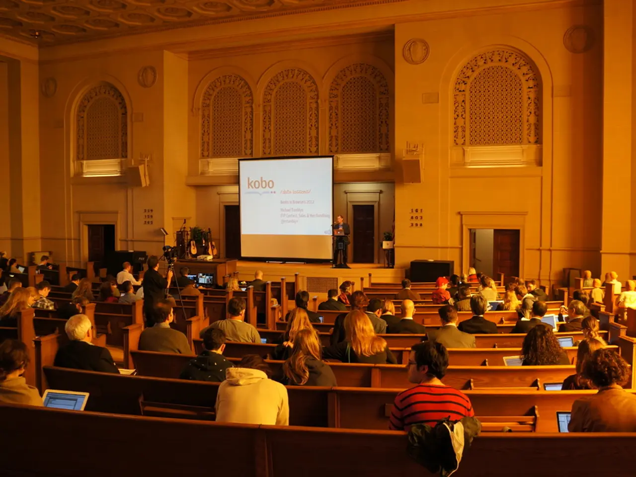 This image is clicked in a building. In this image we can see many persons sitting and using...