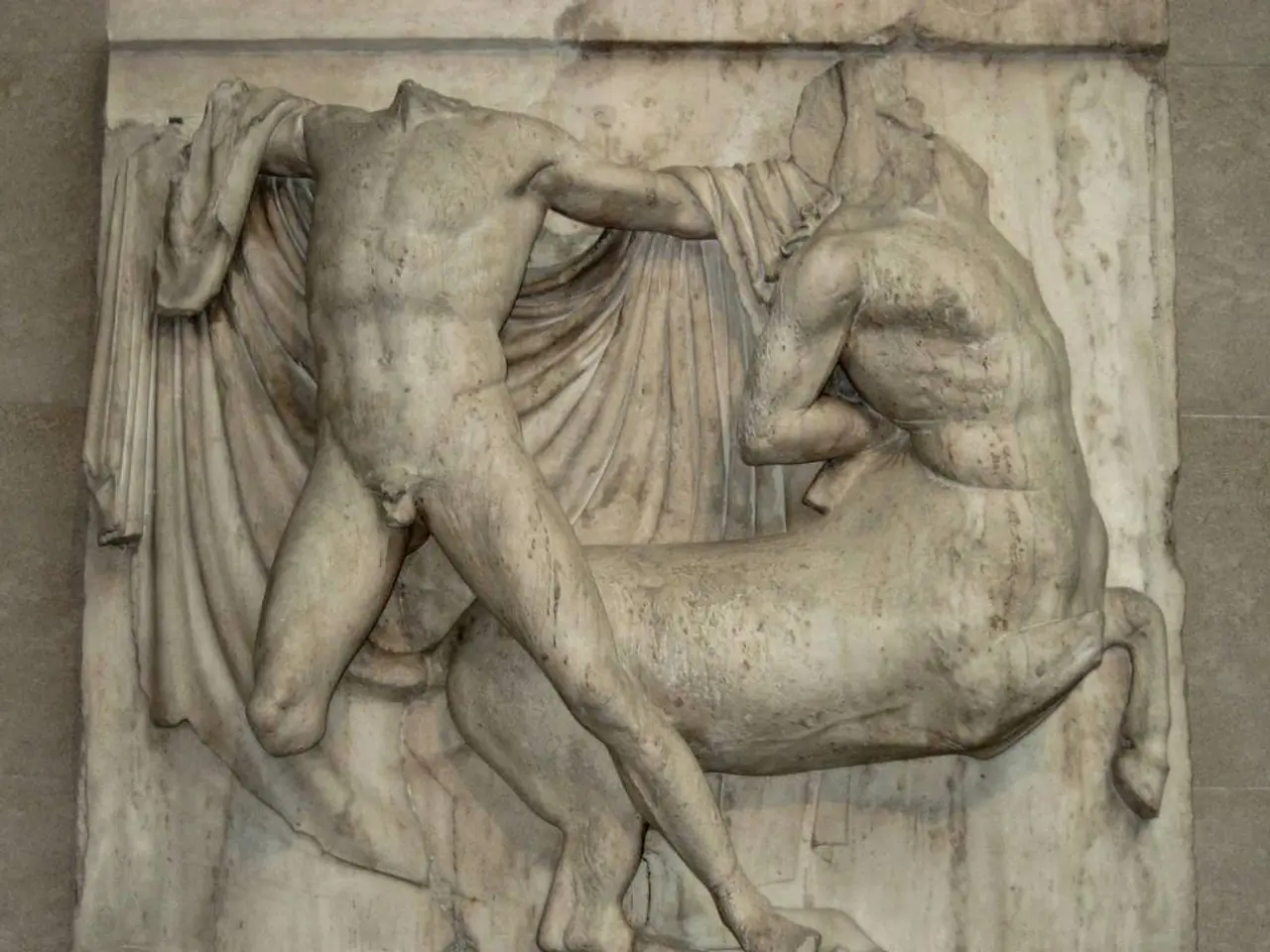 In this image there are sculptures on the wall. At the bottom of the image there is some text.