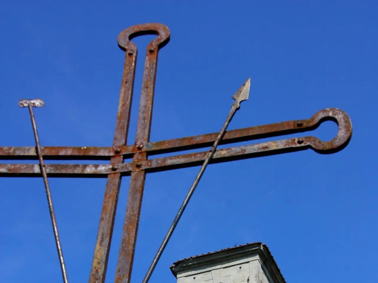 There is a building with brick wall, arch and railing. Also there is a cross with iron rods. There...