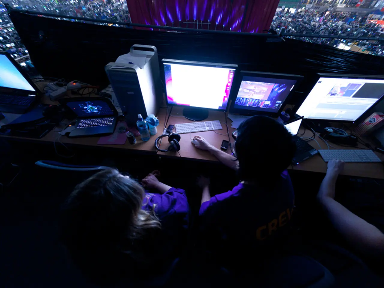 In this image we can see some people sitting on the chairs holding a mouse beside a table...