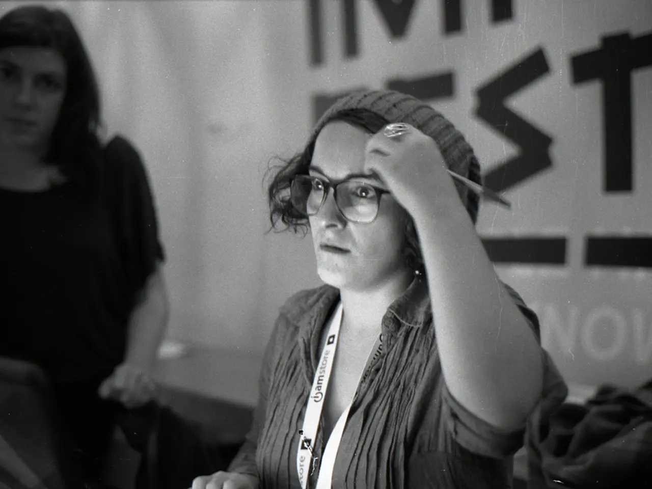 It is a black and white picture of two women and one woman is wearing an identity card. In the...