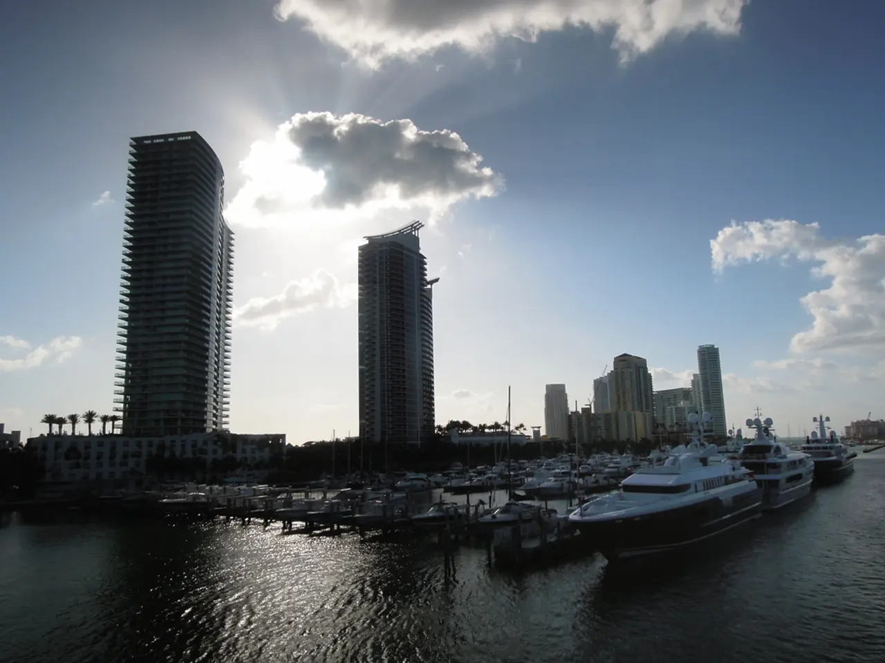 In this image we can see buildings, ships, water, boats, sky and clouds.