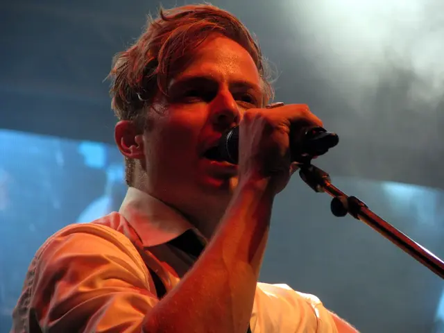 In the center of the image, we can see a man holding a mic and in the background, we can see a...