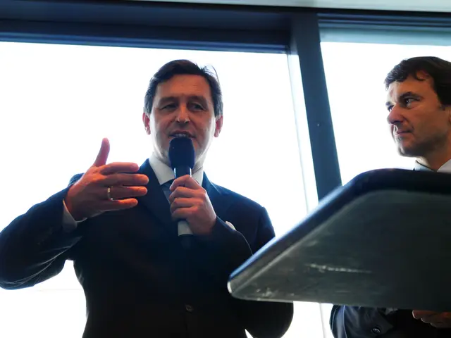 In this picture we can see two men wore blazer where one is holding mic in his hand and talking and...