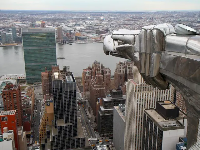 In this image I can see buildings between the buildings I can see a road and there are vehicles...