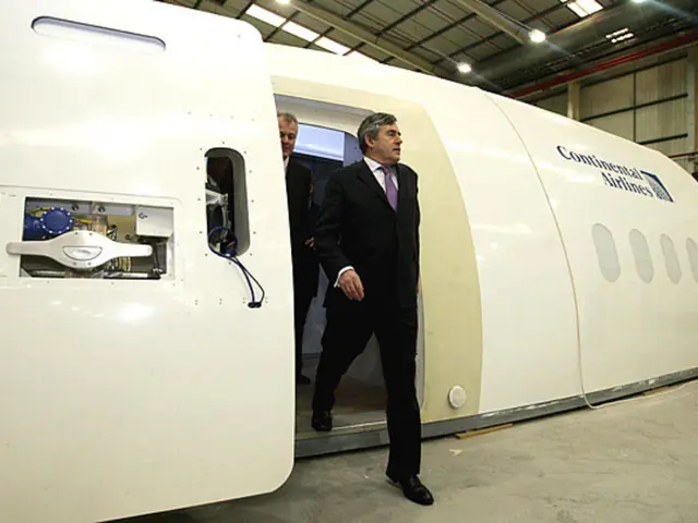 In the center of the image there is an aircraft prototype and we can see two persons. On the...